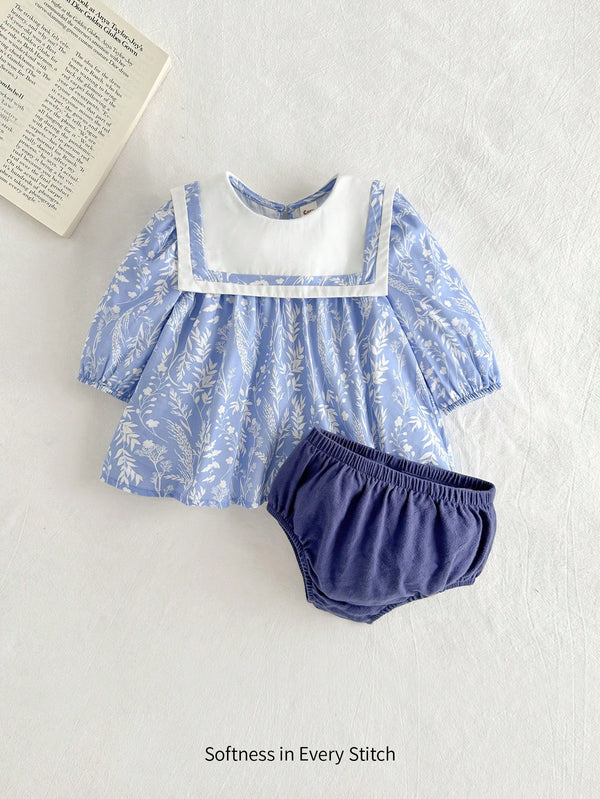 Set i ëmbël për vajza të vogla – bluzë me lule, jakë blu dhe fund me pala, e kombinuar me pantallona të shkurtra për një pamje të freskët dhe të rehatshme verore.